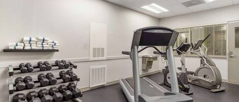 A gym with treadmills, dumbbells, and a mirror.