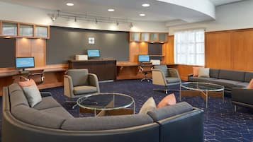 Un hall d’hôtel moderne doté d’un plafond incurvé, d’espaces aménagés pour s’asseoir et d’un comptoir d’accueil.