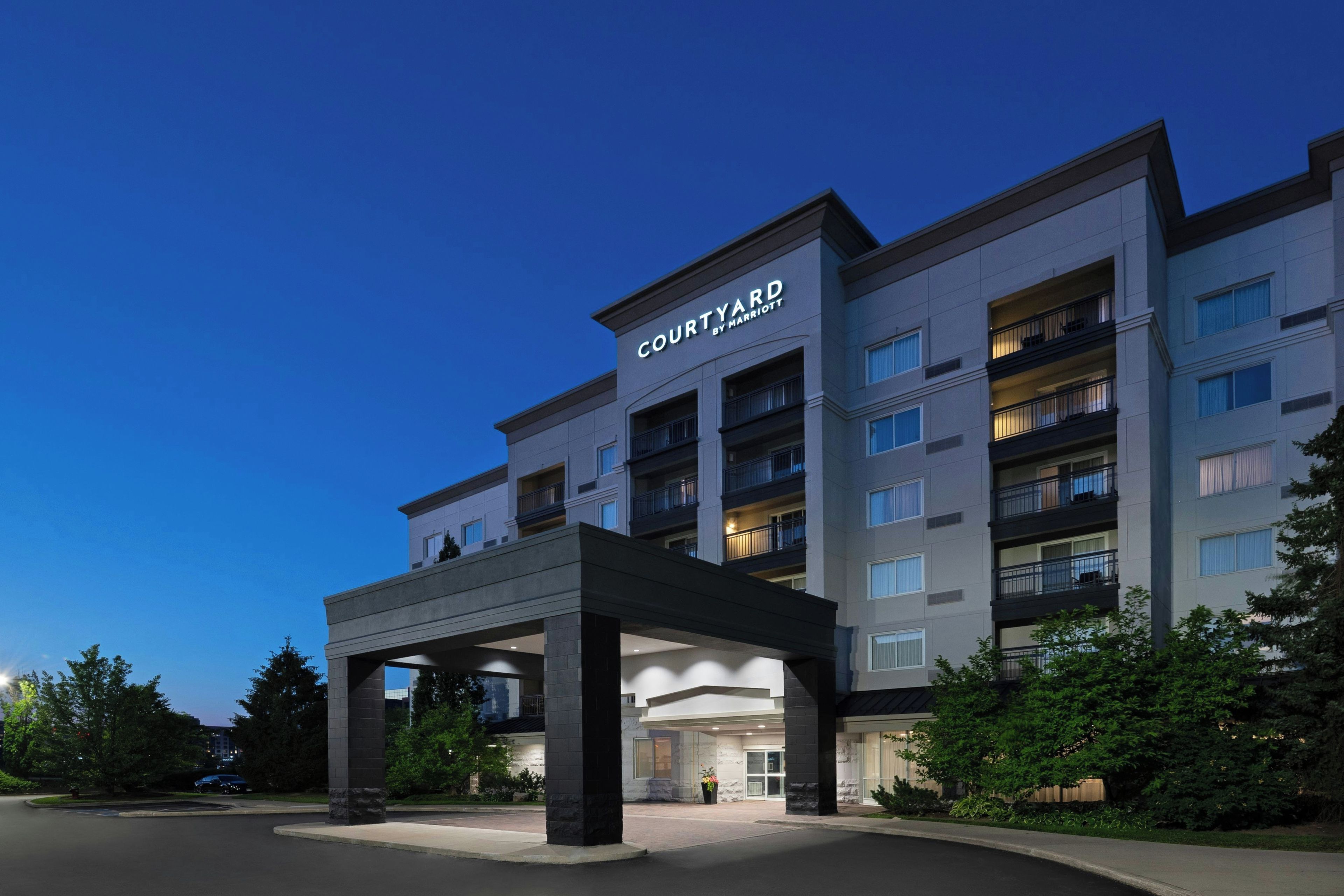 A Courtyard hotel with a modern architectural design, featuring multiple balconies and a covered entrance.