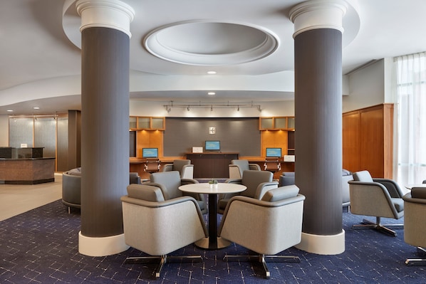 A hotel lobby with a reception desk, seating area, and large columns.