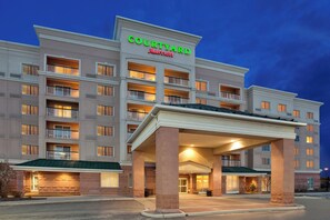 Un hôtel Courtyard Marriott doté de nombreux balcons, d’une entrée couverte et d’une façade bien éclairée.