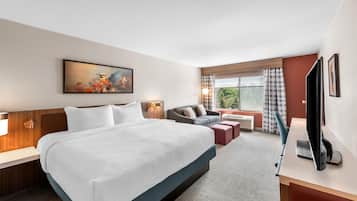 Habitación de hotel con una cama grande, un sofá, un escritorio y un televisor.
