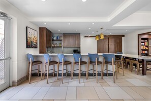 A modern kitchen with bar stools, a dining table, and a kitchen island. - Hilton Garden Inn Overland Park (Overland Park)