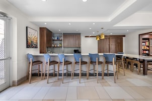 A modern kitchen with bar stools, a dining table, and a kitchen island.