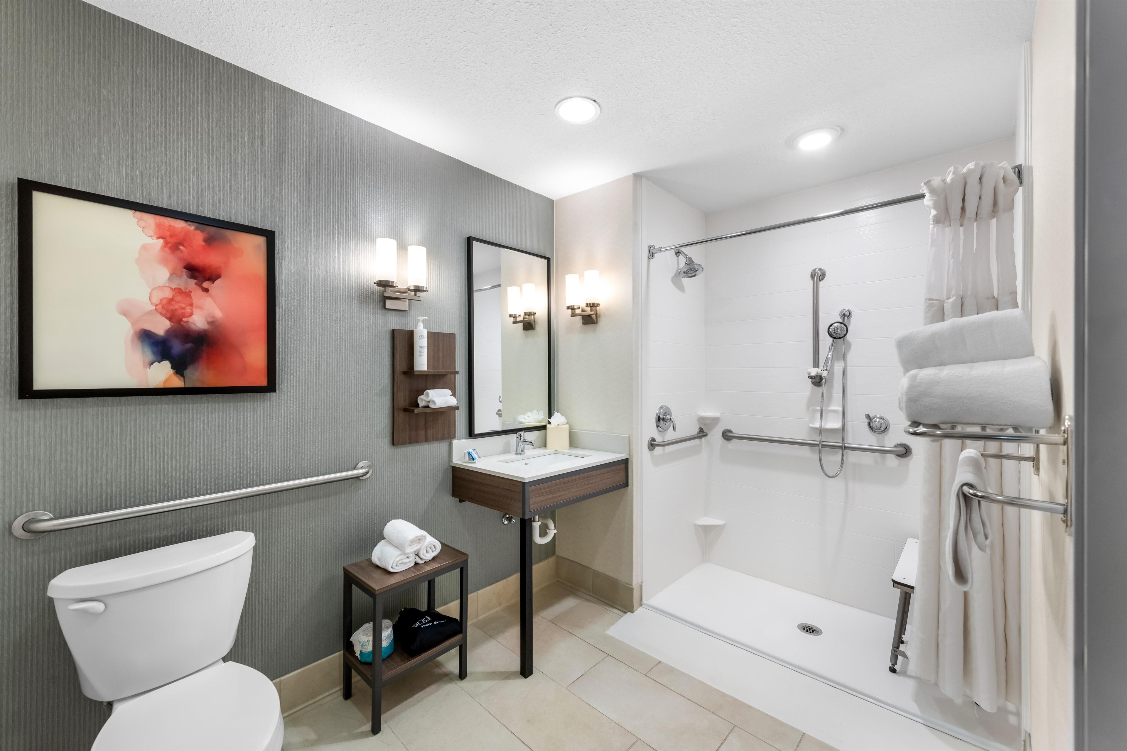 A modern bathroom with a toilet, sink, shower, and a towel rack.
