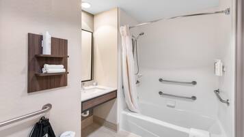 A modern bathroom with a bathtub, a sink, a mirror, and a towel rack.