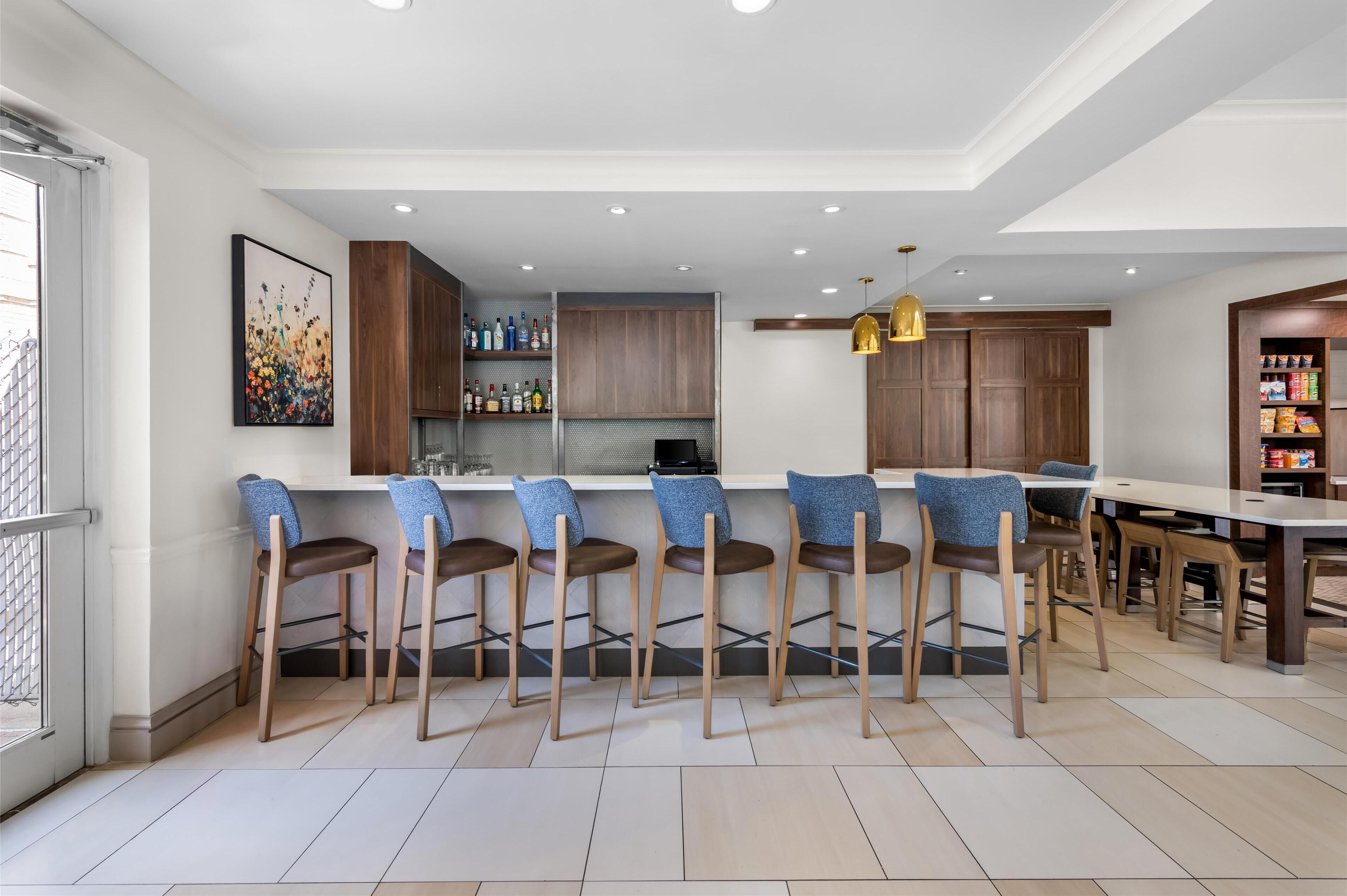 Une cuisine moderne avec des tabourets de bar, des meubles en bois et un coin repas comprenant une table et des chaises.