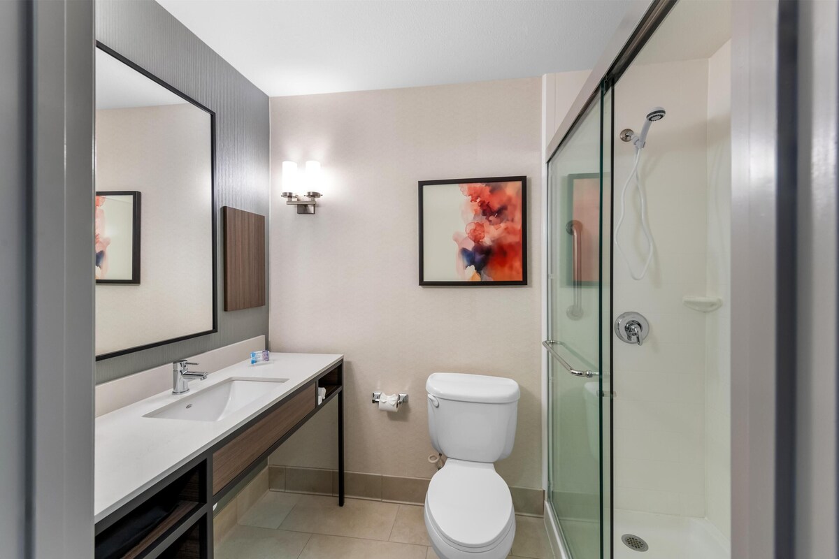 A modern bathroom with a glass-enclosed shower, a white sink, and a toilet.