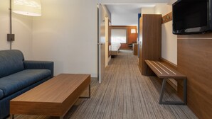 A modern hotel room with a sofa, a wooden table, a TV, and a hallway leading to a bedroom. - Holiday Inn Express & Suites Tucson North – Marana by IHG (Tucson)