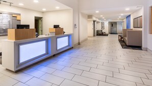 A hotel reception area with a modern design, featuring a reception desk, a refrigerator, and a seating area with a patterned sofa. - Holiday Inn Express & Suites Tucson North – Marana by IHG (Tucson)