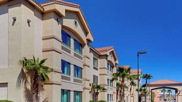 A multi-story hotel with a flat roof, large windows, and palm trees in the foreground.