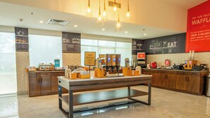 A modern cafe interior with a central table, counter, and various food and drink dispensers. - Hampton Inn St. Augustine Downtown Historic District (St. Augustine)