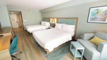 Une chambre d’hôtel avec deux lits, un bureau, une chaise, un canapé et une petite table.