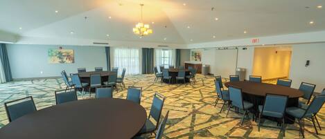 A conference room with multiple tables and chairs, a patterned carpet, and ceiling lights.