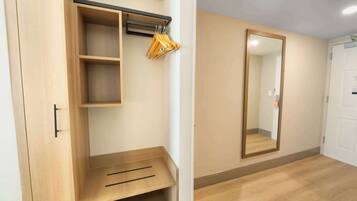 Quarto com guarda-roupa de madeira, espelho e chão de madeira.