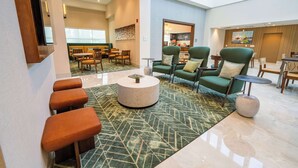A hotel lobby with a seating area featuring green armchairs, a round coffee table, and a bar area in the background. - Hampton Inn St. Augustine Downtown Historic District (St. Augustine)