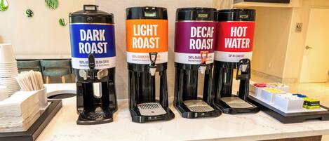 Una estación de café con cuatro dispensadores etiquetados como 'Dark Roast', 'Light Roast', 'Decaf Roast' y 'Agua Caliente'.
