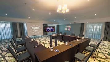 A conference room with a large table, chairs, a projector screen, and a chandelier.