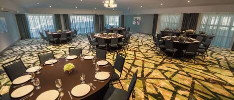 A conference room with round tables, chairs, and a patterned carpet.
