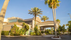 A modern hotel with a covered entrance, palm trees, and a clear blue sky. - Hampton Inn St. Augustine Downtown Historic District (St. Augustine)