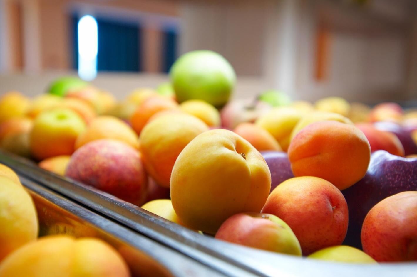 A display of various fruits including peaches and apples in a store.