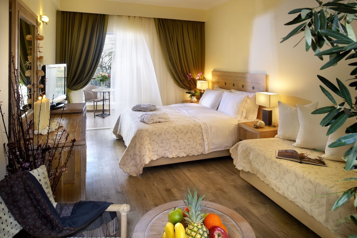 Une chambre d’hôtel avec un lit, des tables de chevet, une chaise et un panier de fruits.