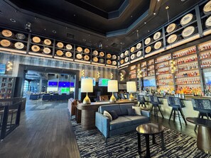 A bar area with multiple seating options, a display of liquor bottles, and a wall of wooden barrels. - Hampton Inn Deadwood at Tin Lizzie Gaming Resort (Deadwood)