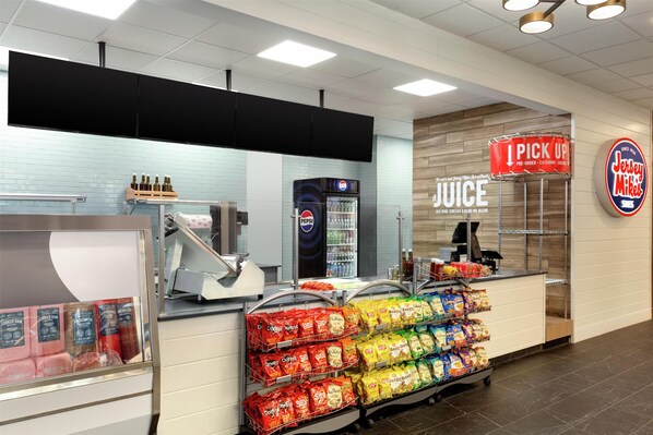 A deli counter with a variety of packaged meats, a Pepsi refrigerator, and a sign for 'I PICK UP'.