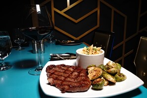 Une table à manger avec un steak, des choux de Bruxelles rôtis et un plat de pâtes.