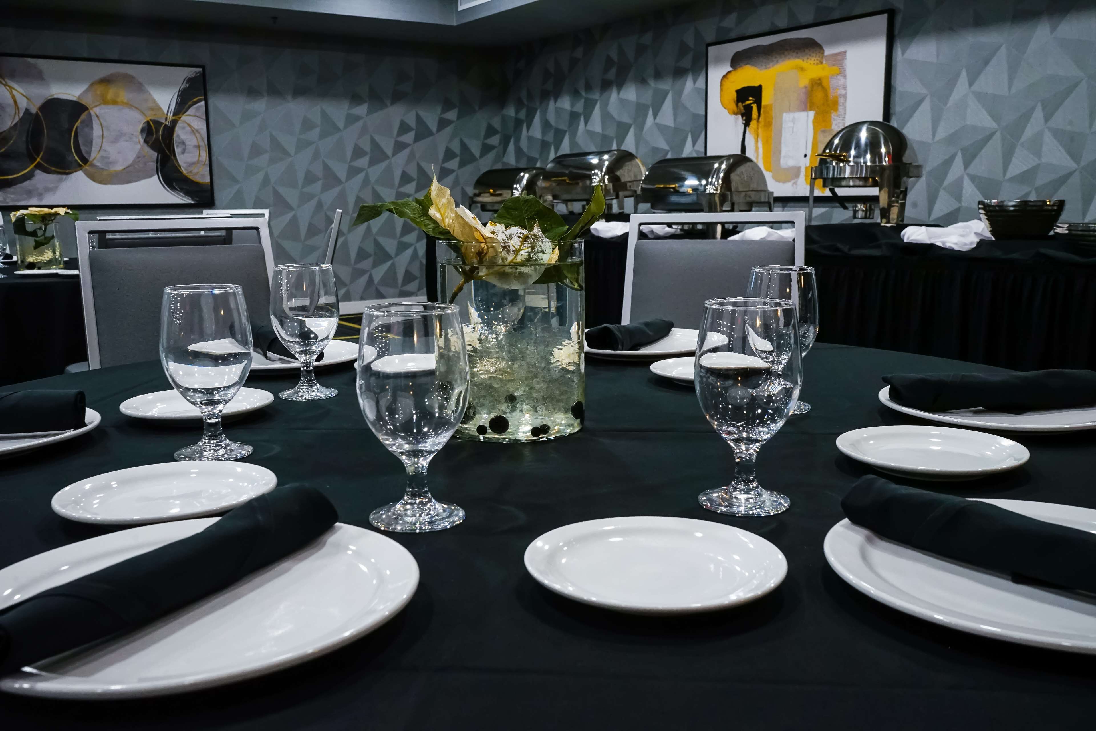 A dining table set with white plates, clear glasses, and a decorative centerpiece.