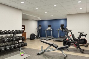 Une salle de sport équipée de tapis de course, d’un vélo elliptique, d’un vélo d’appartement et d’un banc de musculation.