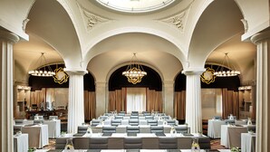 Une salle de conférence avec une longue table, des chaises et un lustre.