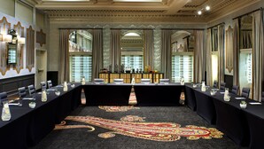 Une salle de conférence avec une longue table, des chaises et un tapis à motifs.