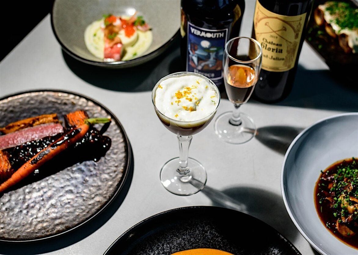 A table with various dishes, a bottle of wine, and a glass of wine.