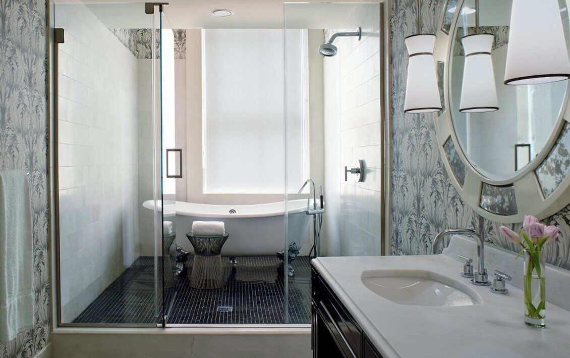 Une salle de bain moderne dotée d’une douche à parois de verre, d’une baignoire sur pieds et d’un meuble-lavabo avec miroir.