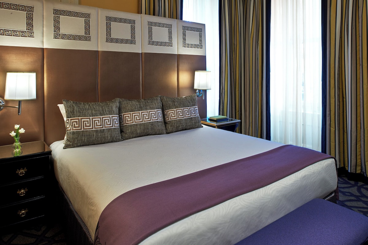 A hotel room with a large bed, two bedside tables, and a nightstand.