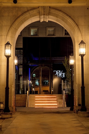 A hotel entrance with a stone archway, glass doors, and a neon sign. - Kimpton Hotel Monaco Washington DC by IHG (Washington)
