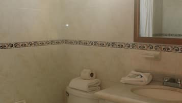 Un baño con inodoro, lavamanos y espejo.