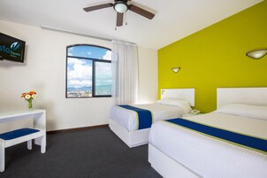 A hotel room with two beds, a desk, a TV, and a window with a view.