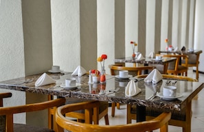 A dining area with marble tables, wooden chairs, and neatly arranged dining ware. - Aranzazu Plaza Kristal Aguascalientes (Aguascalientes)