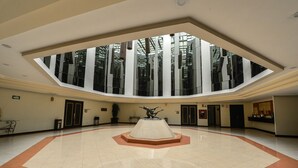 A spacious lobby with a central sculpture, a skylight, and a modern design.