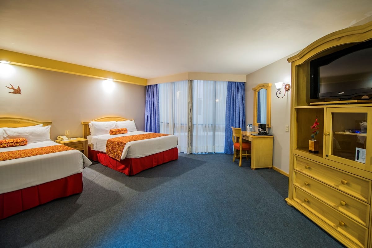 Een hotelkamer met twee bedden, een bureau, een stoel, een televisie en een kast.