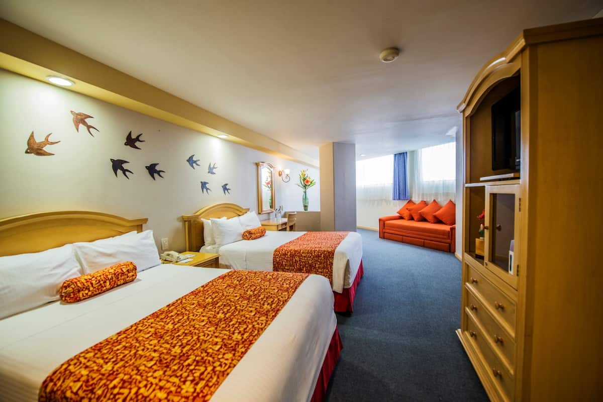 Een hotelkamer met twee bedden, een televisie, een kaptafel en een wand met vogeldecoraties.