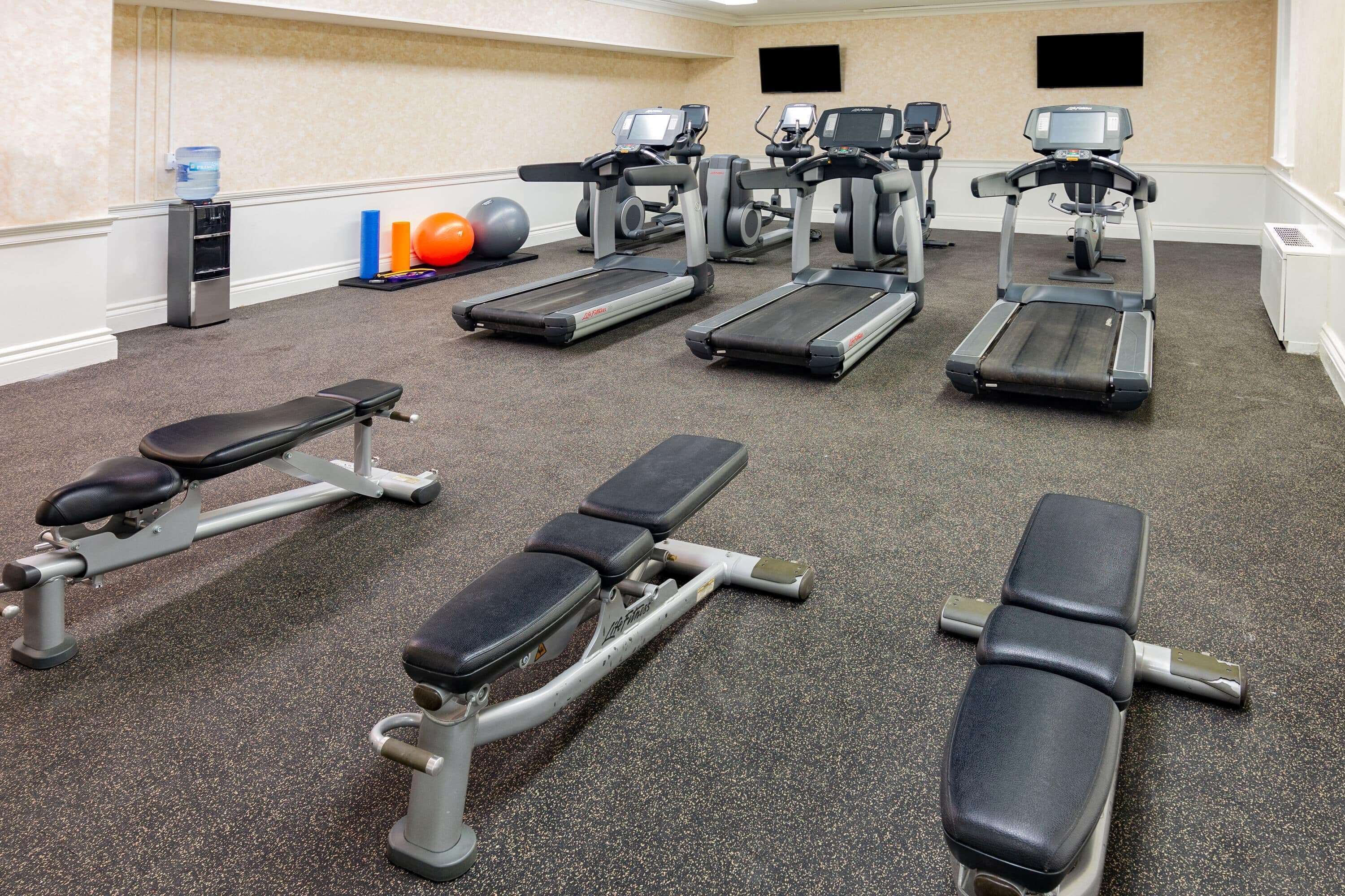 A gym with treadmills, elliptical machines, and weight benches.
