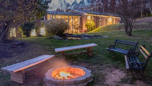 A fire pit with benches, a brick building in the background, and a grassy area. - Natural Bridge Hotel, Trademark Collection by Wyndham (Natural Bridge)