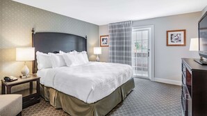 A hotel room with a large bed, two bedside lamps, a nightstand, a dresser, and a window with curtains. - Natural Bridge Hotel, Trademark Collection by Wyndham (Natural Bridge)