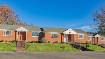 A two-story brick building with a central entrance, a small porch, and a staircase leading to the upper floor.