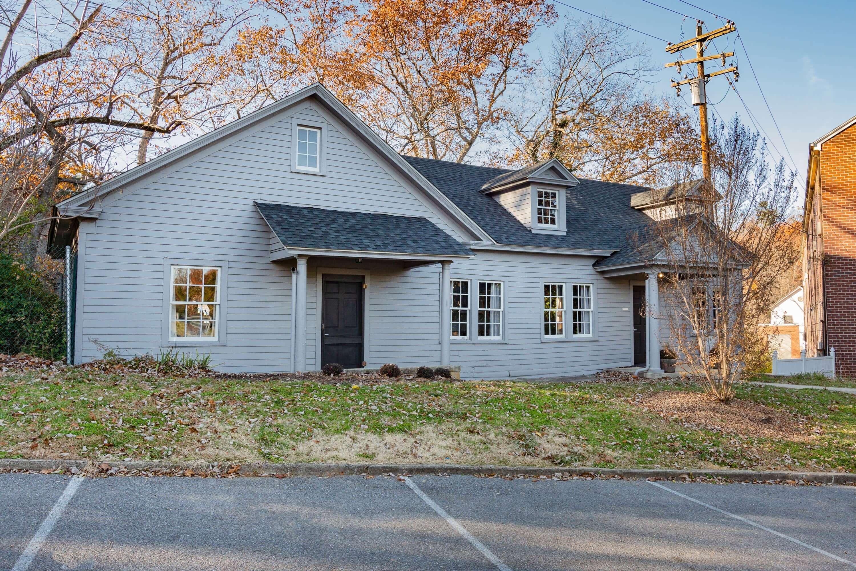 A two-story house with a gabled roof, a front porch, and a small front yard.