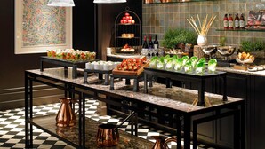 A buffet setup with various food items, a decorative wall, and a checkered floor. - London Marriott Hotel Park Lane (London)