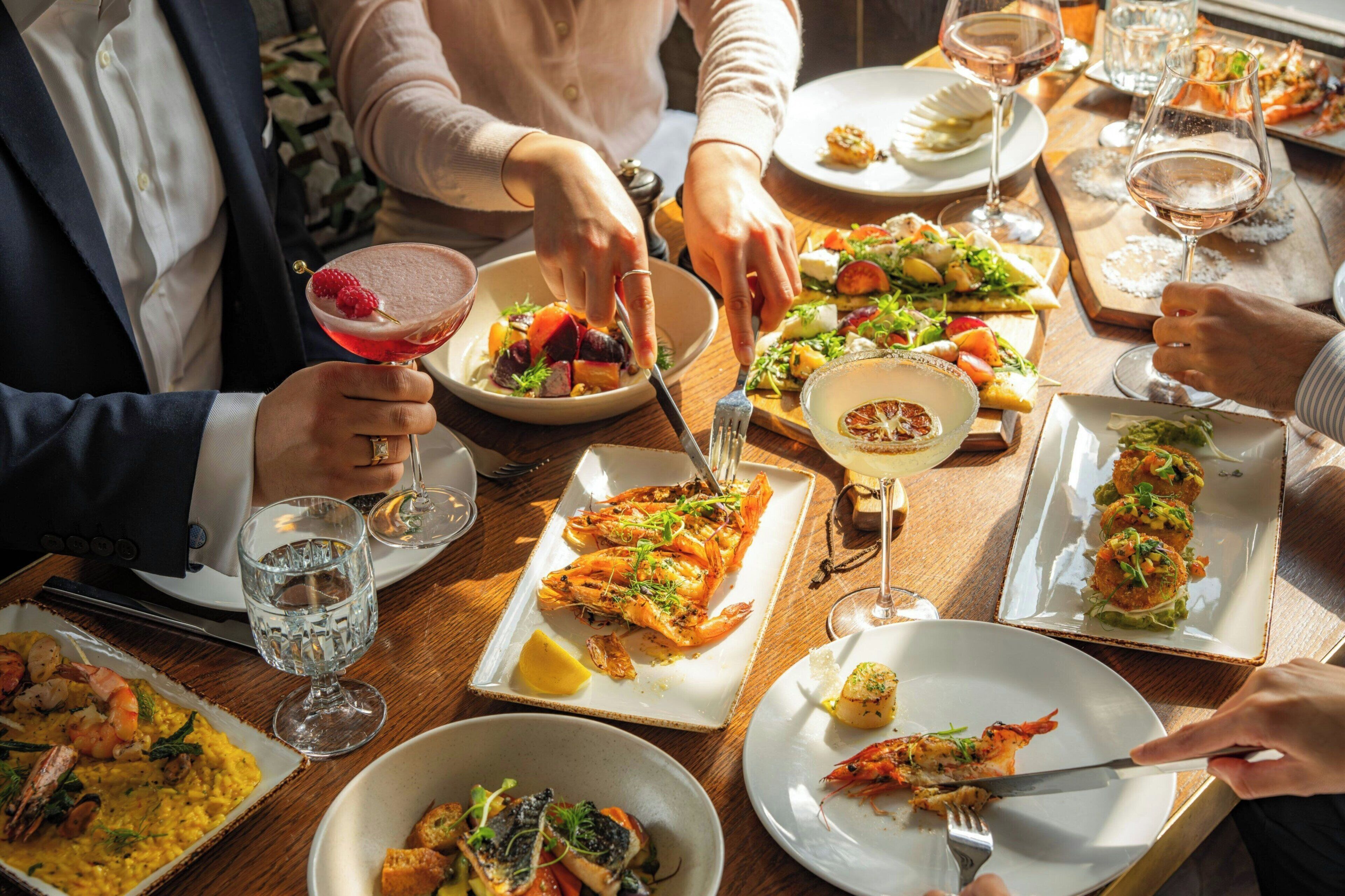 A dining table with various dishes and drinks, including seafood and salads.
